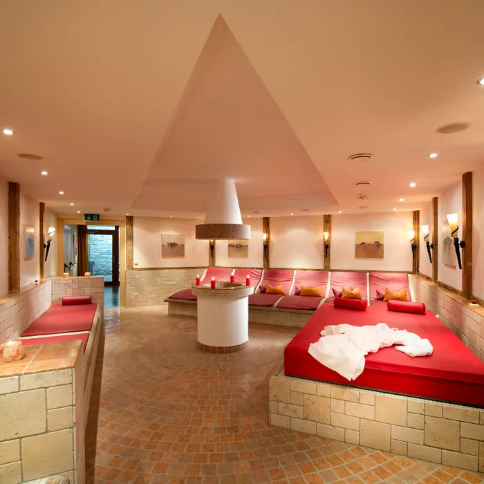 Wellness-Spa-Ruheraum mit roten Liegen, sanfter Beleuchtung und gemütlichem Ambiente